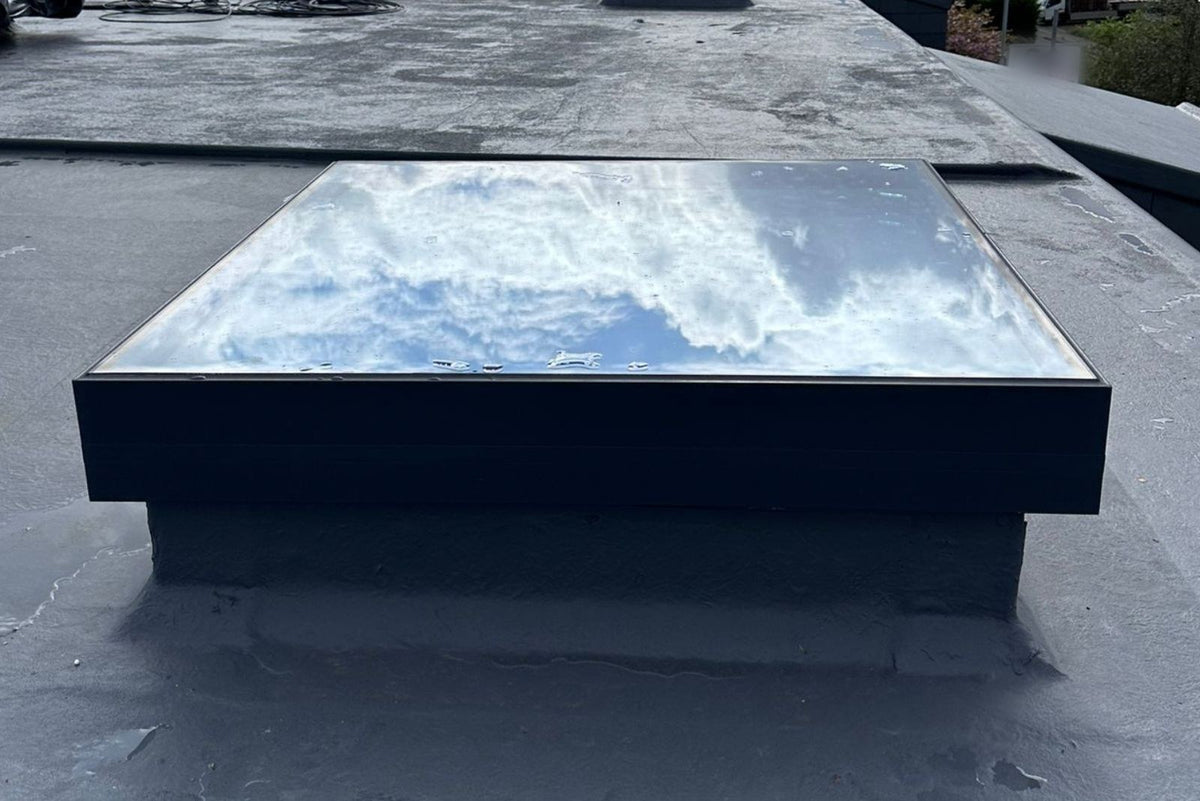 Gerahmtes Flachdachfenster mit Aluminiumrahmen auf gedämmter Aufkantung, Seitenansicht auf dem Flachdach