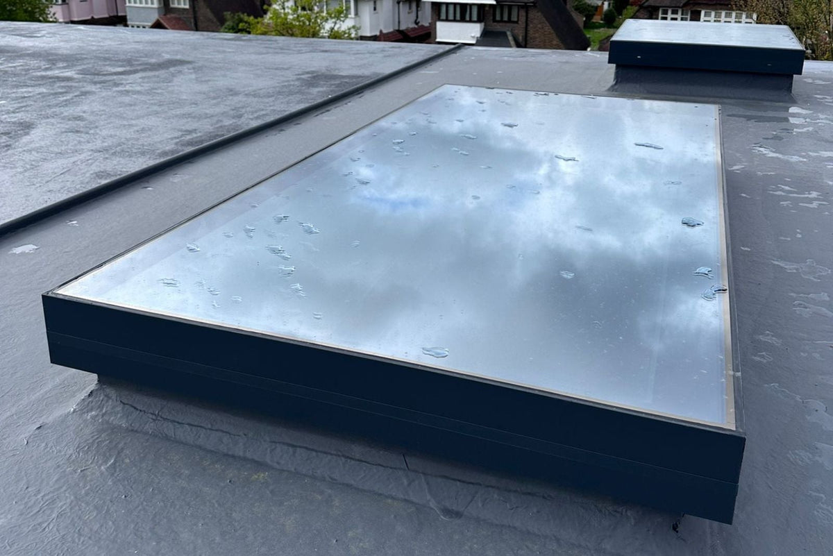 Gerahmtes Dachfenster im abgedichteten Flachdach, Regentropfen auf der Verglasung