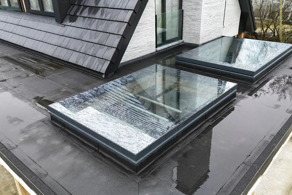 Zwei elektrisch öffnende Dachfenster mit Aluminiumrahmen auf einem Flachdach, geschlossen